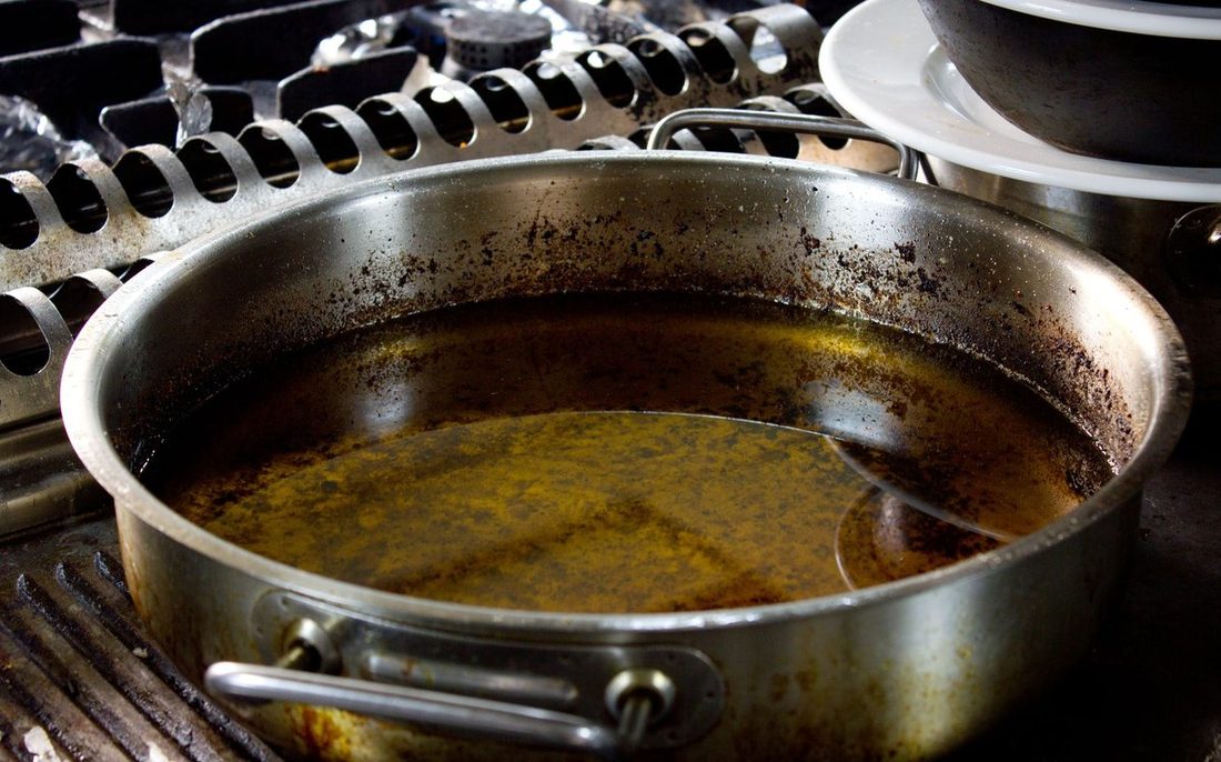 A pan of used cooking oil on a kitchen stove