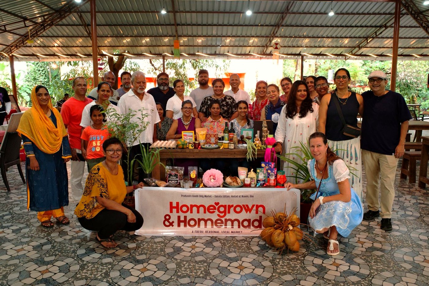 Vendors and organisers of Homegrown & Homemade Market gathered around the market banner with their products
